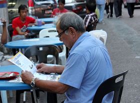 老居民拿到法輪功真相資料後，開始認真地閱讀起來。