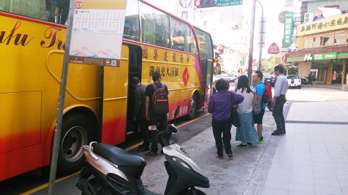 法輪功學員（中間穿紫色上衣，手拿資料者）給正在上車的大陸遊客派發真相資料。