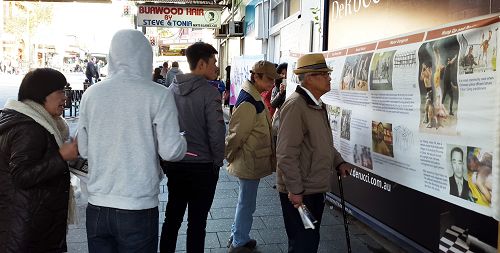 圖4：黃埔軍校六級畢業生胡老先生（正中頭戴禮帽者）正在認真閱讀真相橫幅。