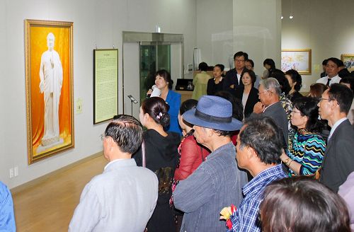 '圖2：前來觀看美展的各界人士在認真聽解說員講解每幅畫的背景。'