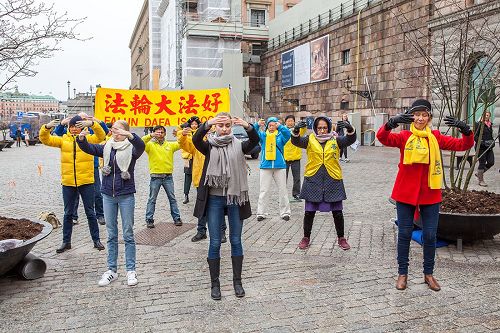 '圖1：瑞典法輪功學員在斯德哥爾摩最熱鬧的皇宮旁的錢幣廣場舉辦法輪大法信息日活動。圖為法輪功學員正在演示第二套功法──法輪樁法。'