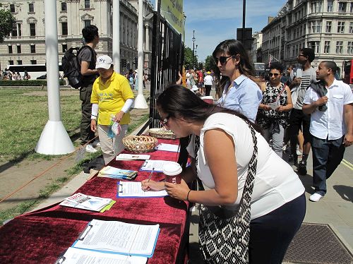 '圖4：二零一七年七月十八日，美國遊客利茲﹒卡薩諾瓦（Liz Casanova）在英議會大廈經過時，簽名支持制止中共迫害法輪功及其活摘器官罪行。'