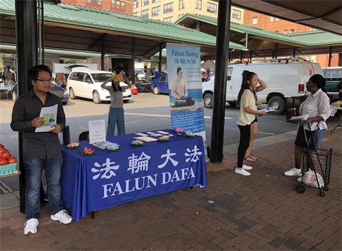 '圖：明州法輪功學員在當地的農貿市場設置展位，介紹功法'