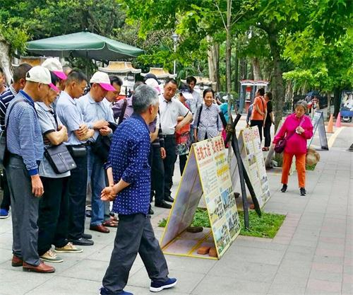 '圖2：中國大陸遊客一批一批的在真相展板前駐足'