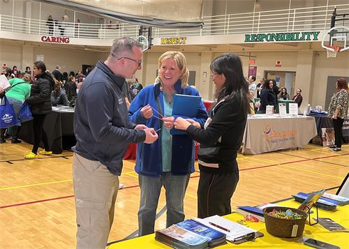 圖3：新澤西州州眾議員卡羅爾﹒墨菲（Carol Murphy）（中）拜訪法輪功展位，並接受法輪功學員贈送的功法傳單和精美小蓮花。（法輪功學員提供）