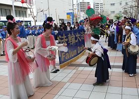 天國樂團在旗頭陣現場演奏，仙女並發送繫有「法輪大法好」卡片的蓮花書籤。