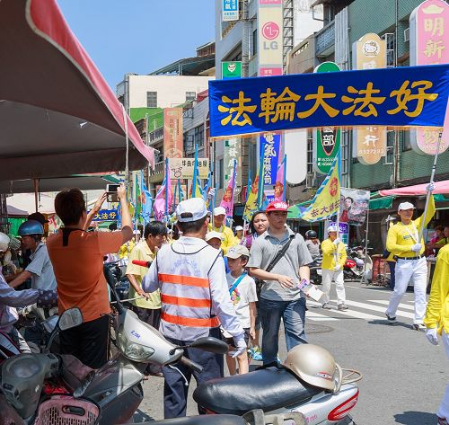 不少民眾遠遠聽到法輪功洪法隊伍鼓樂聲，早已聚集路旁等待隊伍的到來，高舉著手機、相機拍照留念。