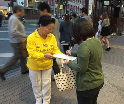 圖1-2：日本民眾聽了法輪功學員講迫害真相後，簽名舉報迫害元凶江澤民