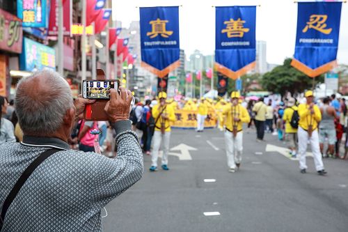 '圖4：淡水環境藝術節遊行，「真、善、忍」隊伍最受矚目，不少民眾拿出手機拍照留影。'