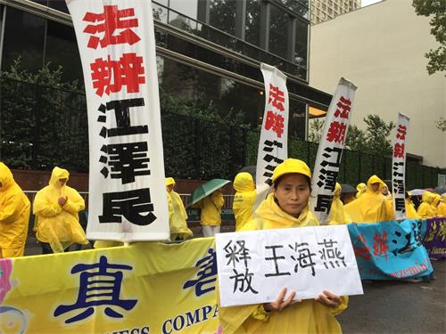 '圖5：在當天的抗議活動中，來美六個月的山東義齒製造技師呂彩雲手中舉著一個牌子，兩面分別寫著「釋放王海燕」和「釋放徐秀娟」。'