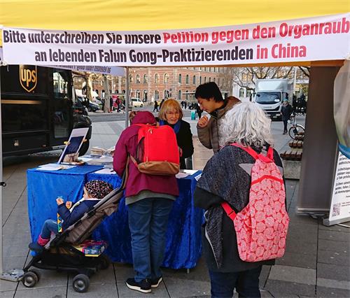 '圖6：推著嬰兒車的易得黑姆﹒烏哈姆女士在反對中共活摘器官的請願書上簽名'