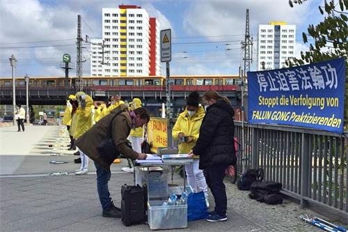 '圖2：二零二一年四月二十三日，路過的民眾得知中共活摘法輪功學員器官的罪行後，在學員的請願書上簽字，譴責中共暴行。'