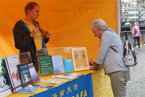 '圖2：二零二二年十月底，法輪功學員在蘇黎世舉辦信息日活動，路人簽名要求制止迫害法輪功。'